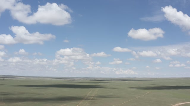 Perfect day of fluffy clouds handing over an open field. American landscape.