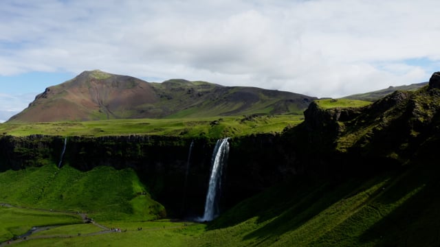 Majestic waterfall rolling off of hilltop in Iceland. 