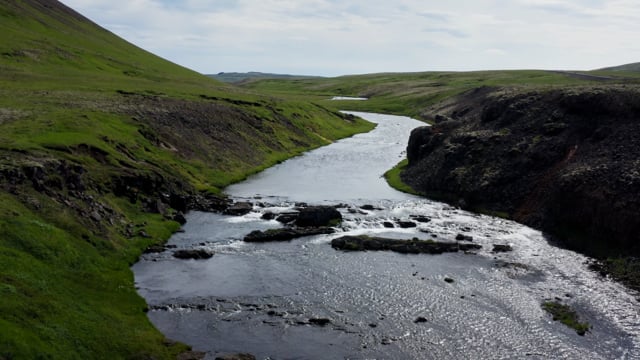 Massive Icelandic river runs towards a powerful waterfall.