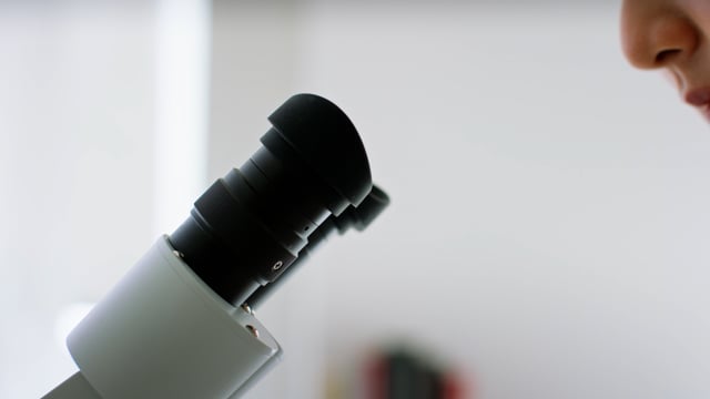 Asian Female Scientist uses her microscope to examine new molecules. 