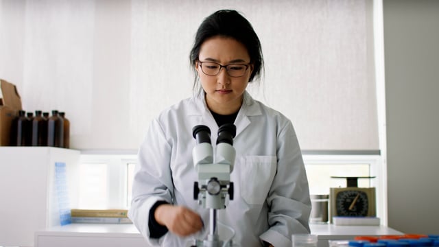 Scientist uses their microscope to examine new molecules. 
