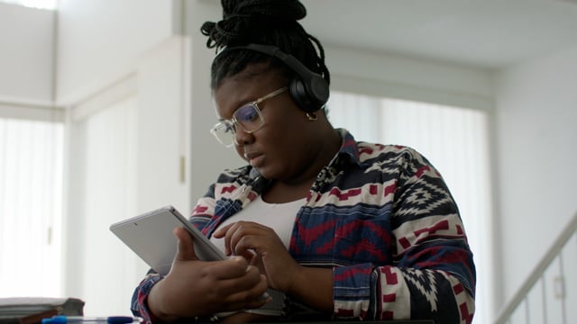 Young black woman working on her tablet from home. 