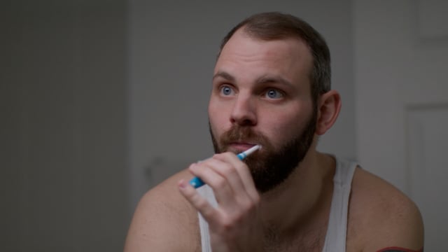 Young Caucasian Male brushes his teeth in during his morning routine