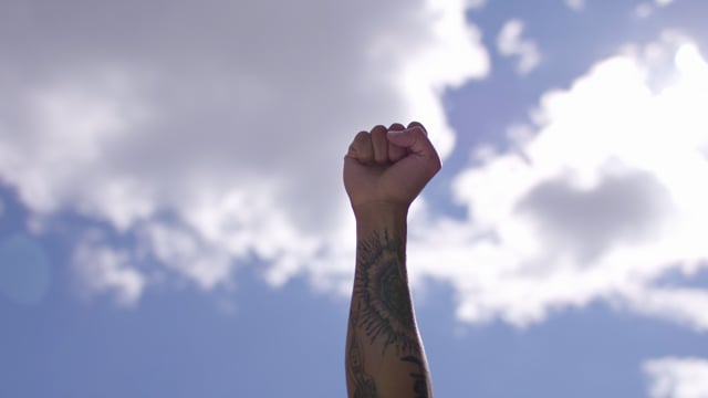 A clenched fist of a black man defiantly raised in the air as a political gesture and sign of protest, activism and solidarity. 