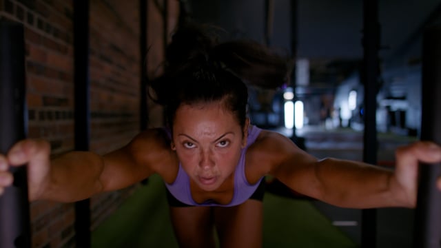A determined young female athlete challenges her limits by pushing a weighted sled. 