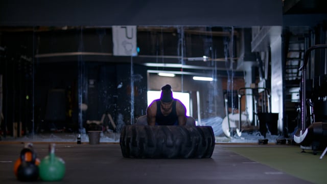 Strong and capable male athlete lifting tractor tire for exercise. Pushing yourself. 

