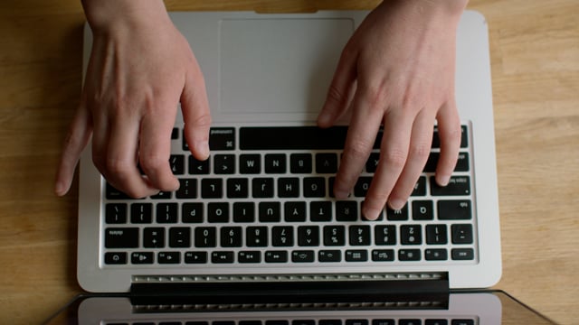 Woman typing a message on a laptop. Closeup of a typing process on a grey laptop. 