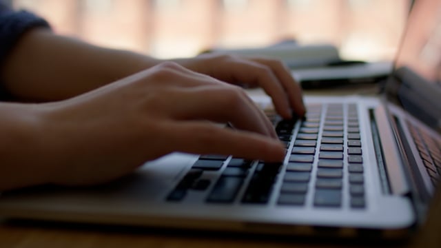 Woman typing a message on a laptop. Closeup of a typing process on a grey laptop.