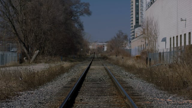 Empty train tracks along an isolated urban building. 
