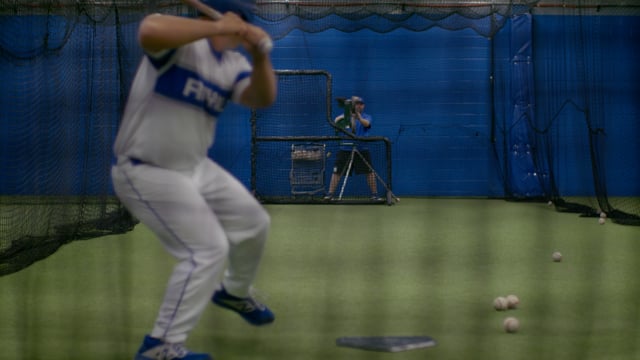 Athletic baseball player practicing his swing in a training facility. 