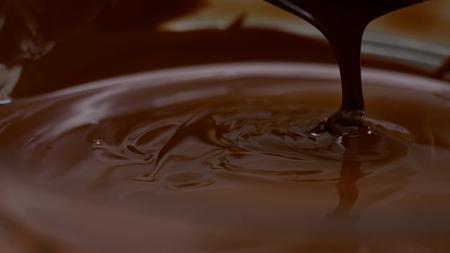 Decadent melted chocolate is mixed in a mixing bowl. 

