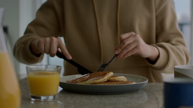 Young woman chilling in her condo, enjoying a pancake brunch. 