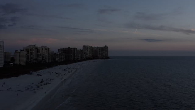 A beautiful coastal sunset in Florida, the beaches peppered with people.   