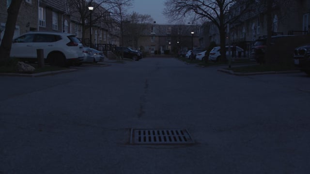 An empty street with parked cars in a residential area. Day-night matching. Night shot 2 of 2.