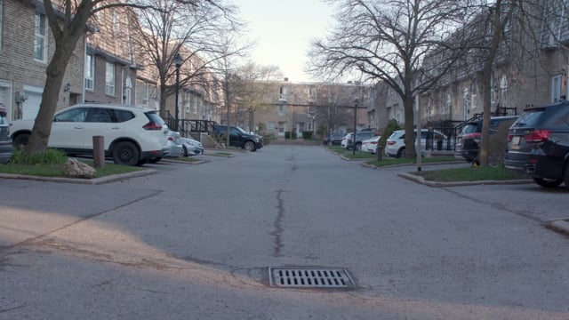 An empty street with parked cars in a residential area. Day-night matching. Day shot 1 of 2