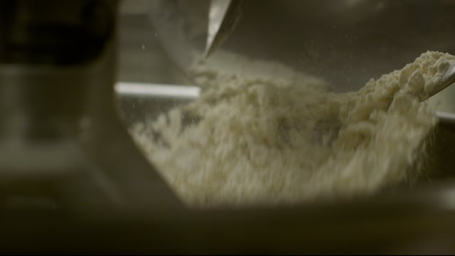 Flour tumbles from the mixing bowl and into the industrial mixer as the baking ingredients come together. 