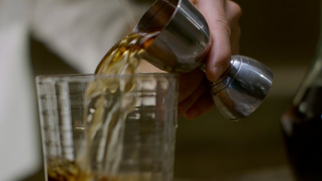 Pouring a shot of liquor into a rocks glass as a delicious cocktail is prepared. 