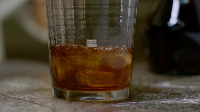 Ice falling into a rocks glass as a delicious cocktail is prepared. 