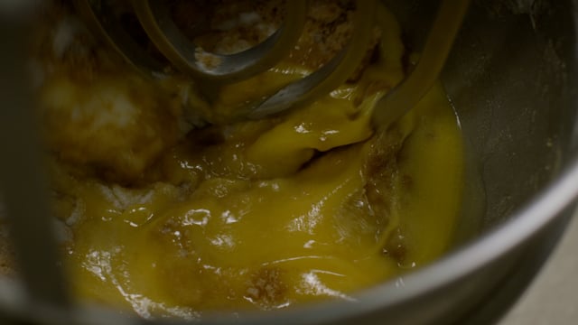 Melted browned butter is poured into the mixer as the baking ingredients come together. 
