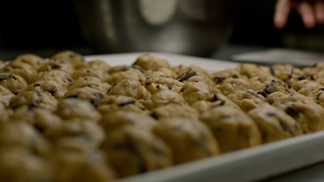 Carefully formed balls of cookie dough are arranged on a tray, ready to be baked. 