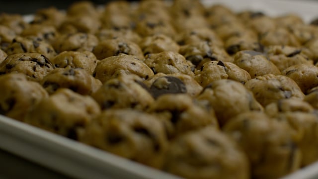 Carefully formed balls of cookie dough are arranged on a tray, ready to be baked. 
