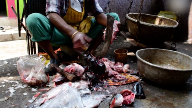 A worker chops up fish at New Market fish market, Kolkata, India, 2022