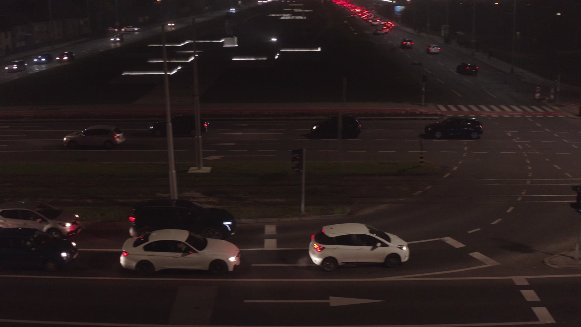 Night traffic, cars waiting and changing lanes, panned view of the avenue