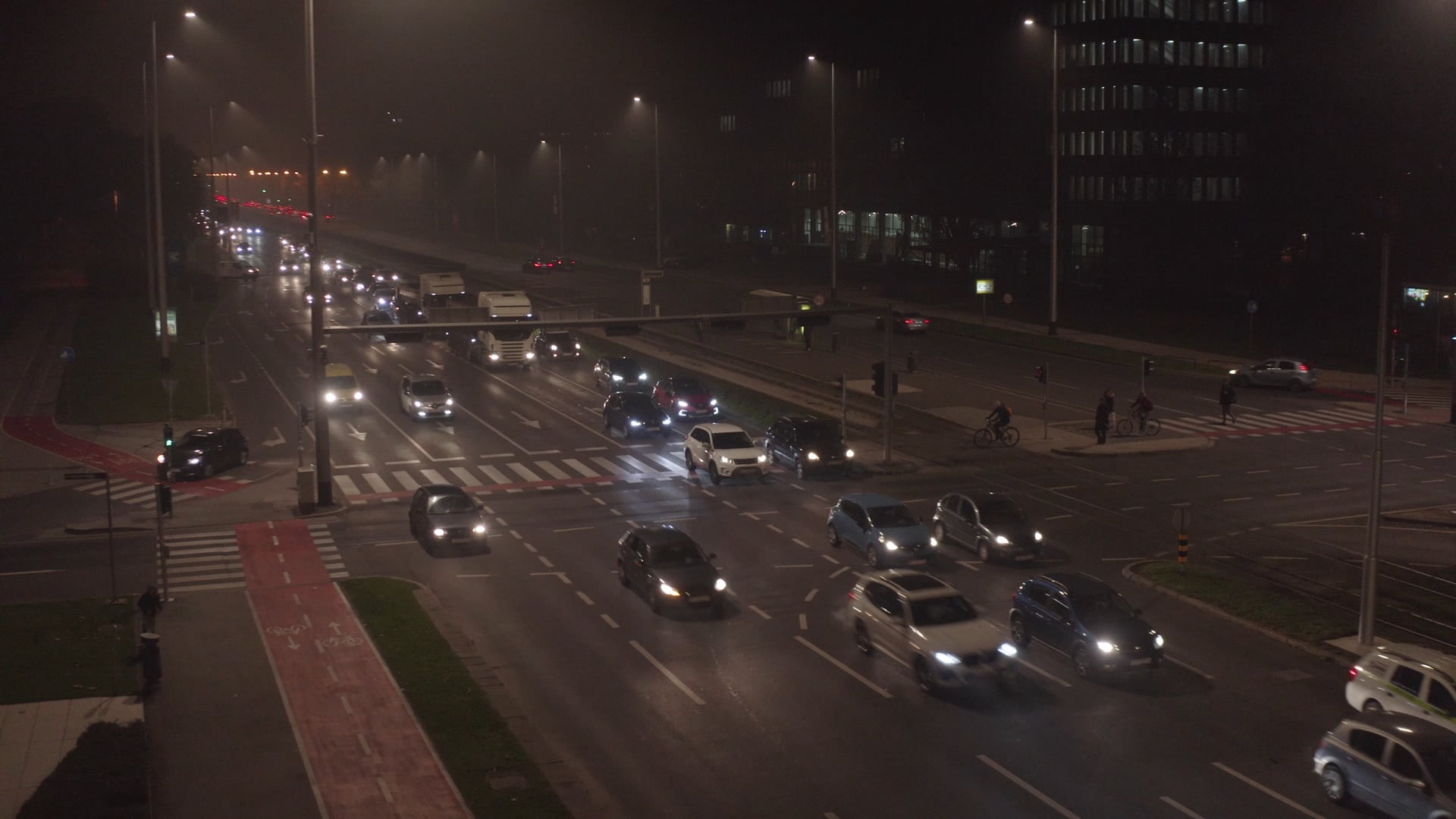 Night traffic, cars stoping on the red light, panning to the other side of the crossroad