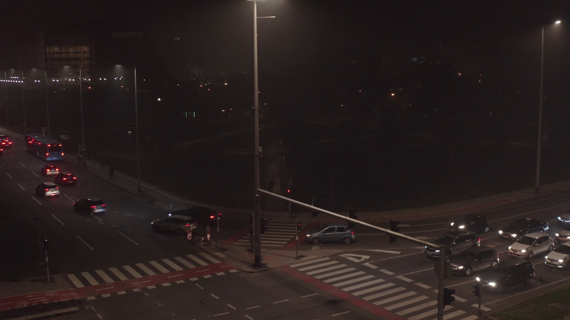 Night traffic, cars waiting on the red light, person running accros the pedestrian crossing
