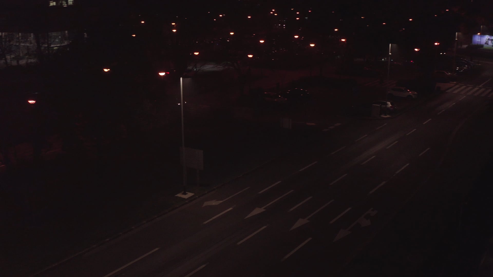 Night traffic, shot tracking a cyclist into darker area of the road, few cars visible there