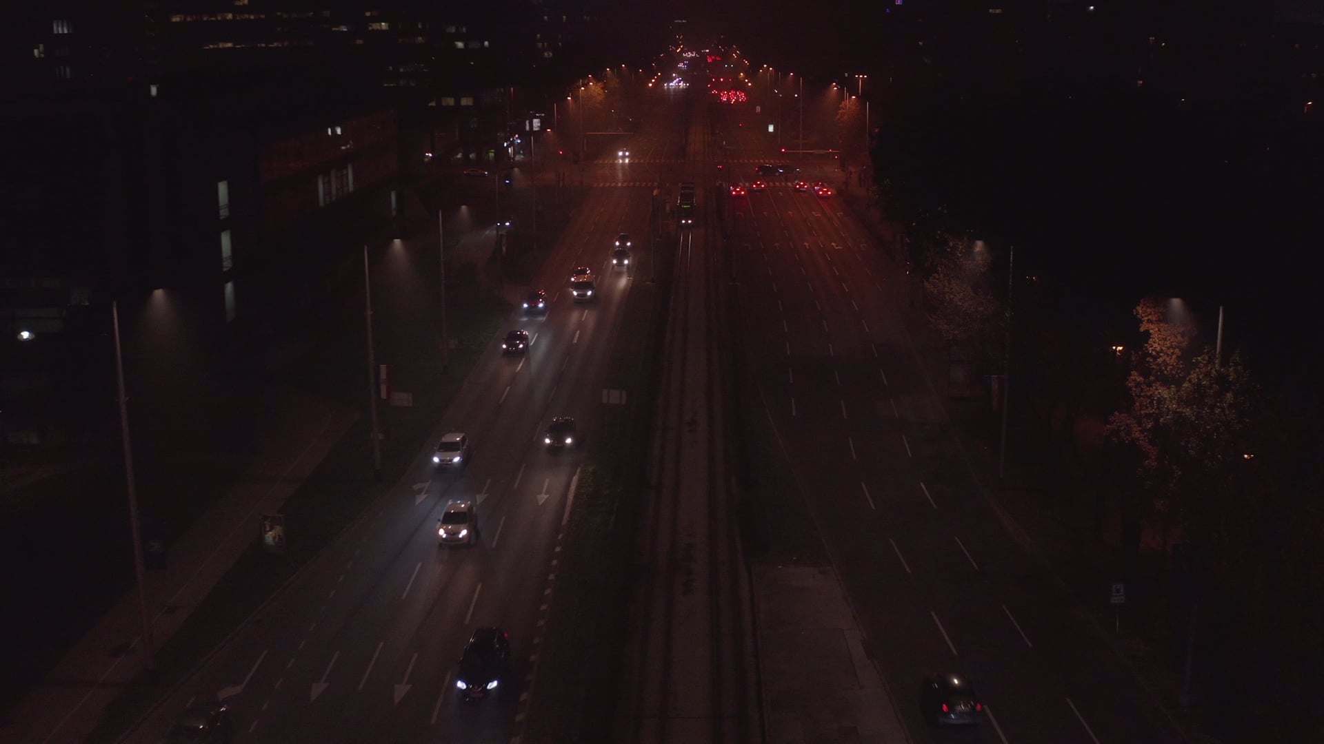 Night traffic, tram stopping on the tram station, cars moving on the road