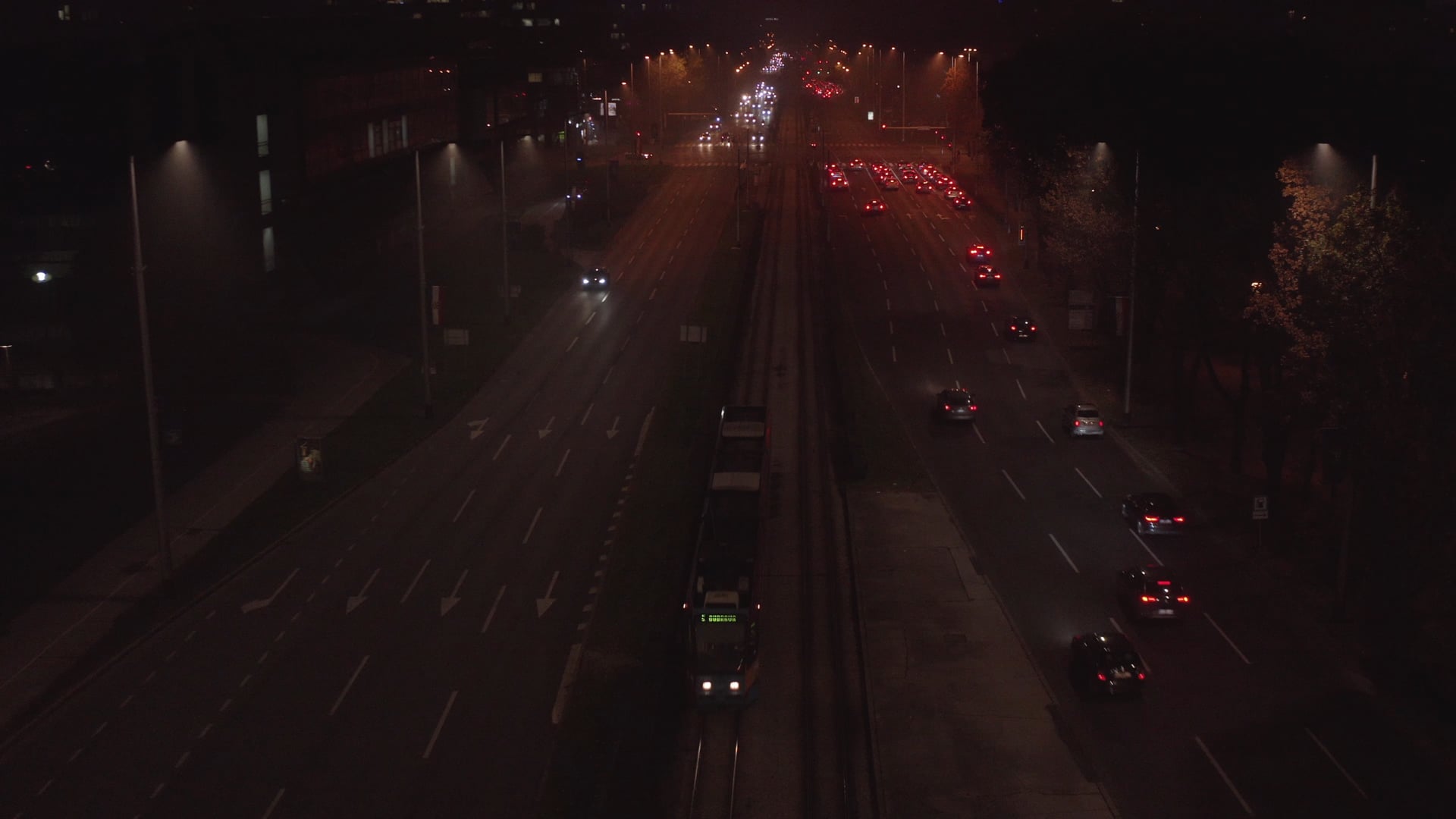 Night traffic, tram leaving the tram station and moving out of the frame, steady shot