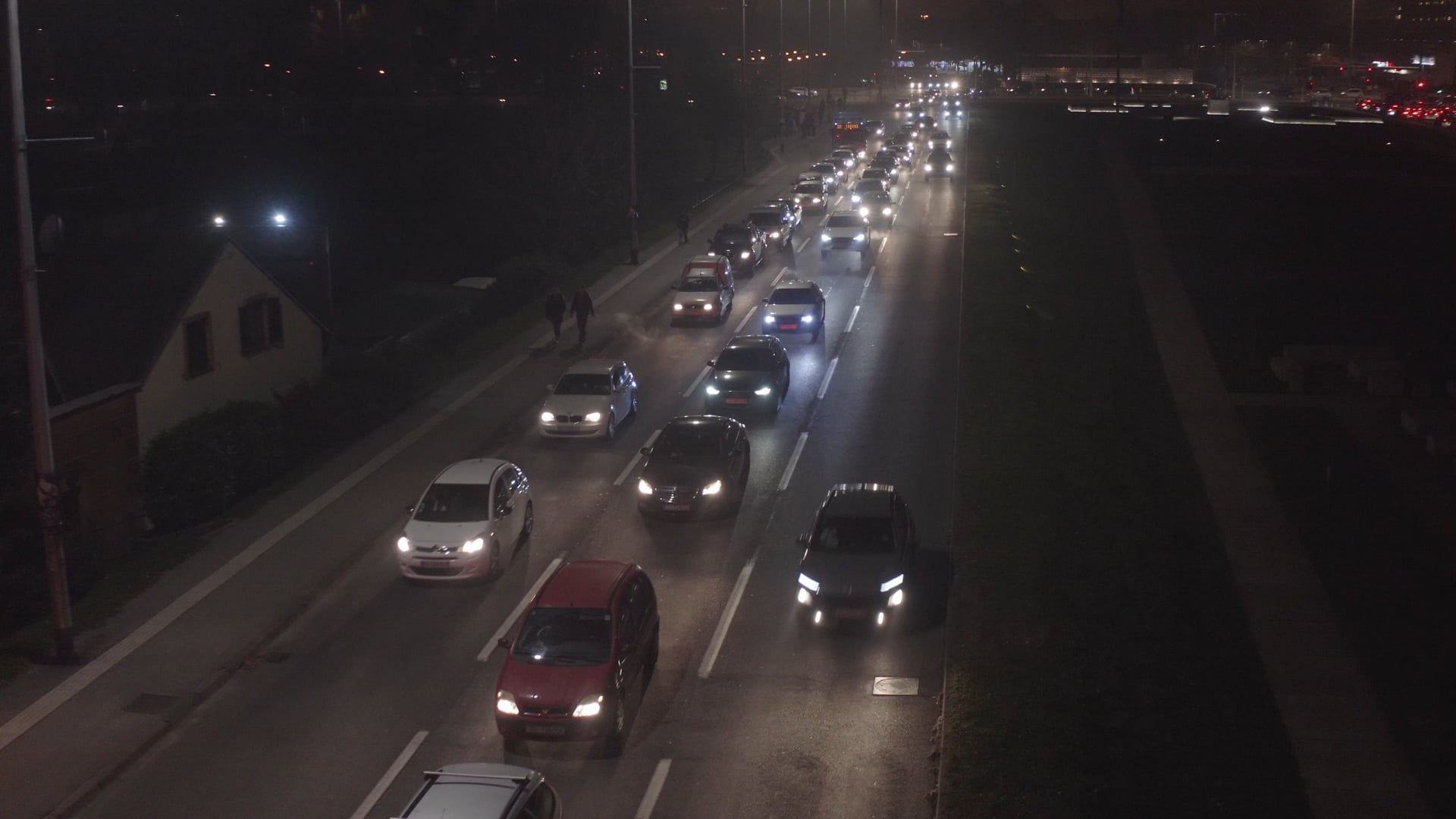 Night traffic, cars moving slowly, people walking on the pedestrian