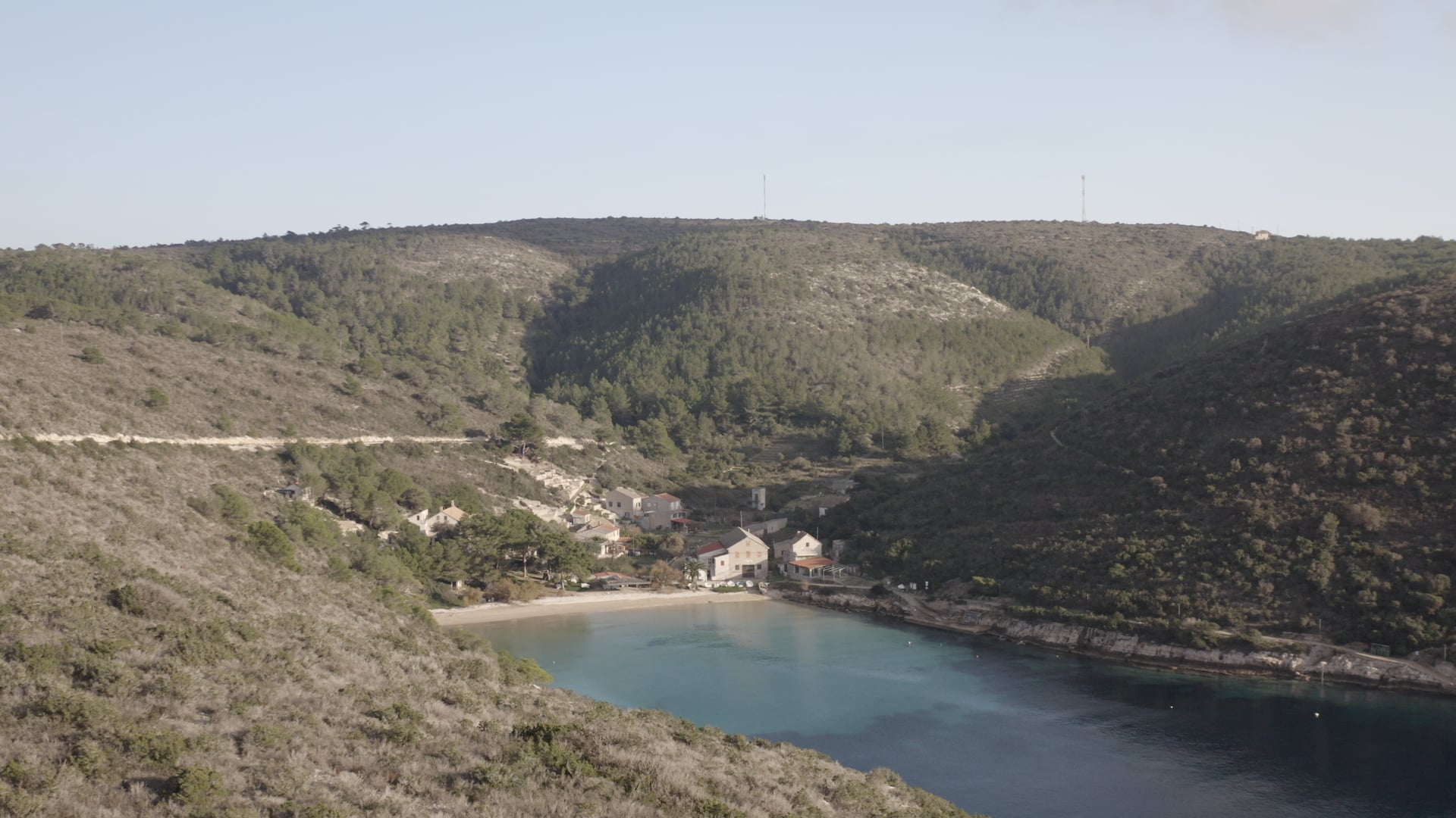 Approaching the small beach, crystal clear blue sea, forest in the background