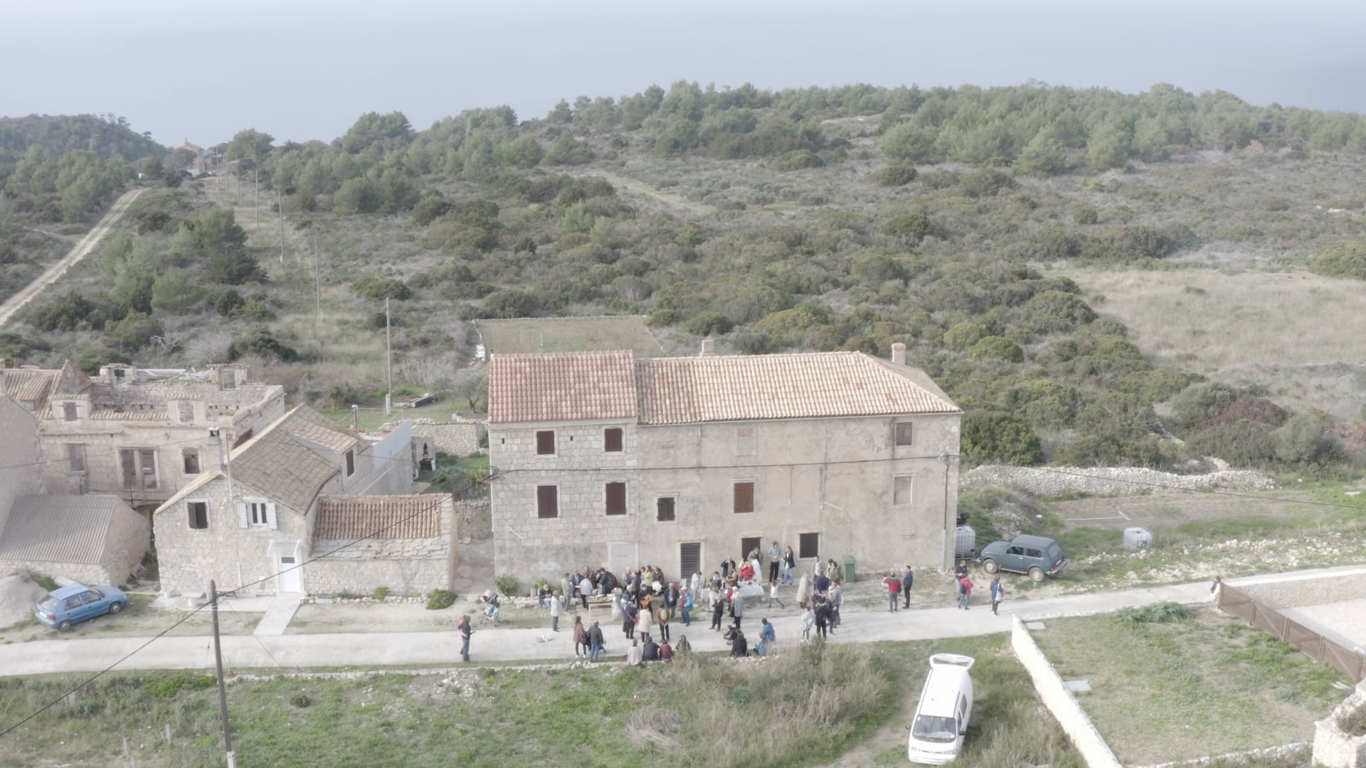 People standing, talking, having fun on the road in front of the house, slowly panning right