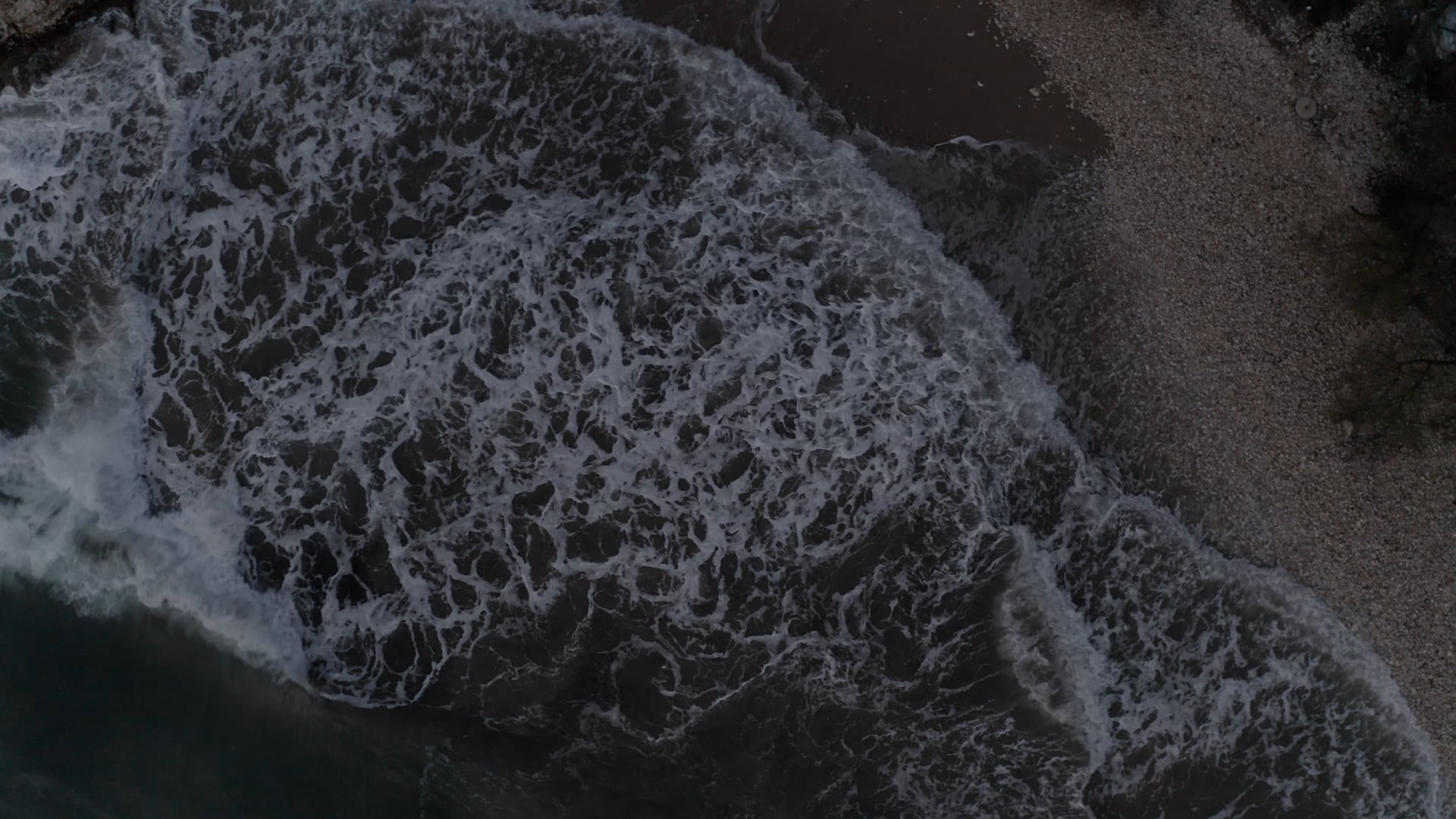Waves splashing the pebble coast, dark blue foamy sea
