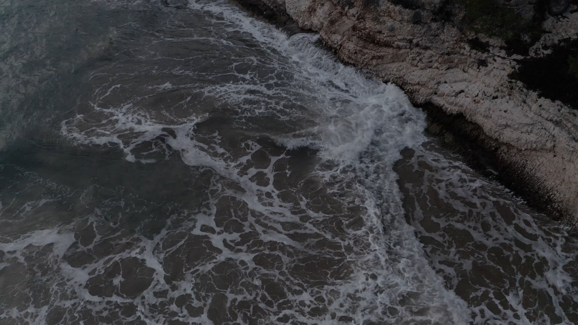 Waves crashing at the stone cliff, close up, foamy sea