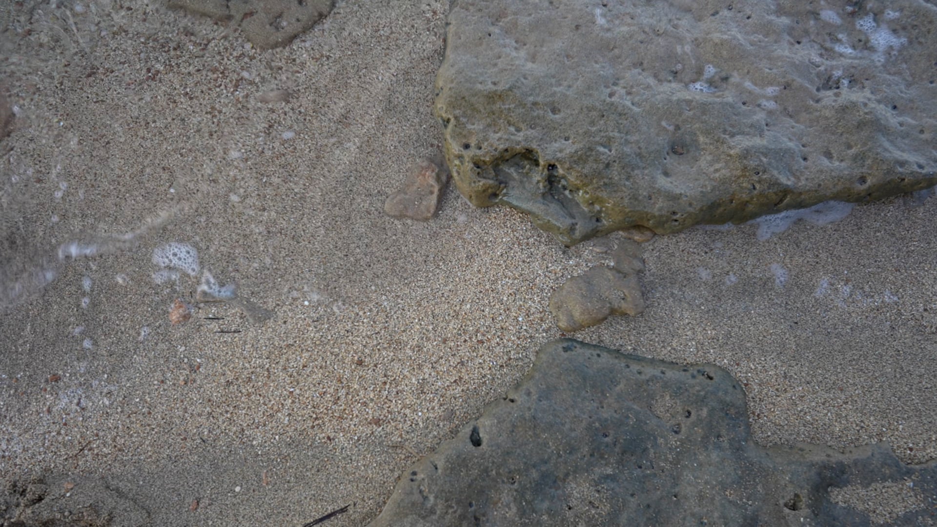 Close up, waves barely reaching the sand and pebble beach, crystal clear sea