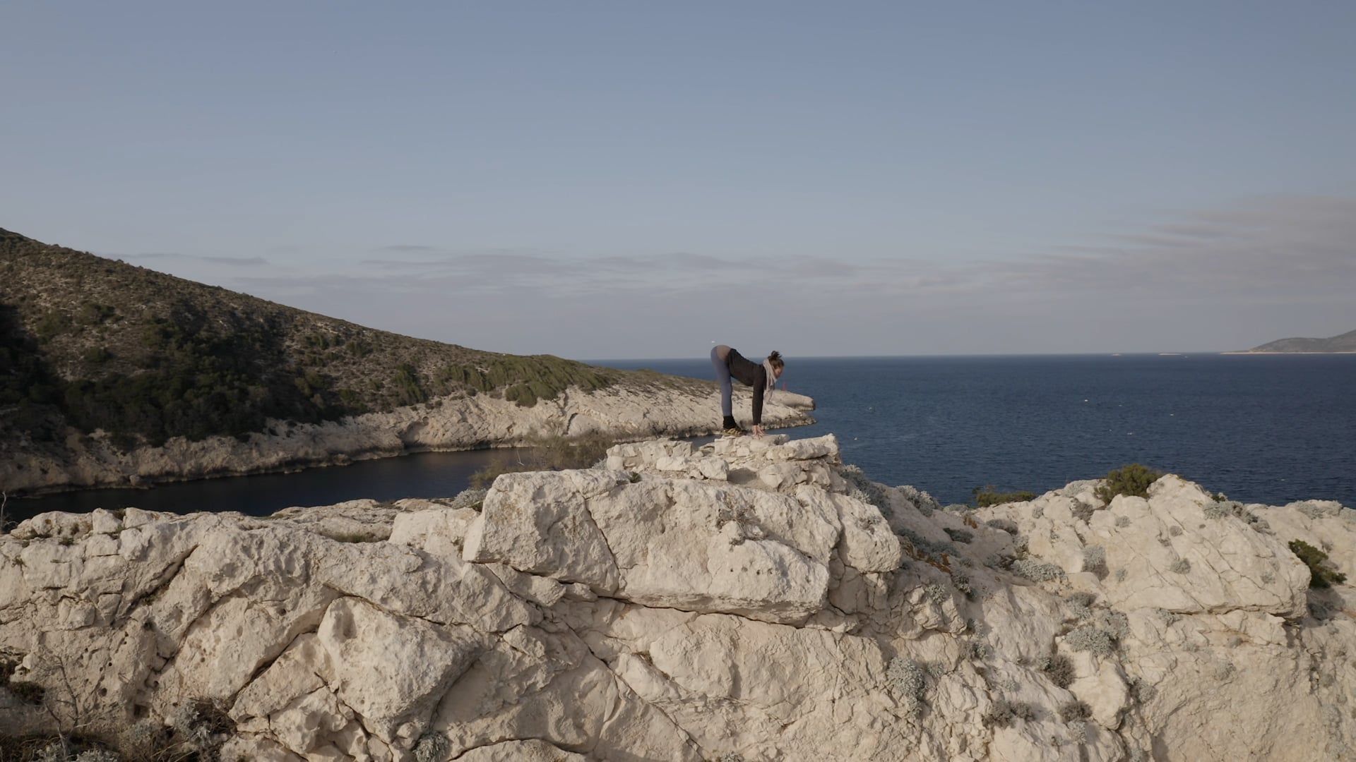 Woman doing yoga on the top of the cliff, seagulls flying over the sea