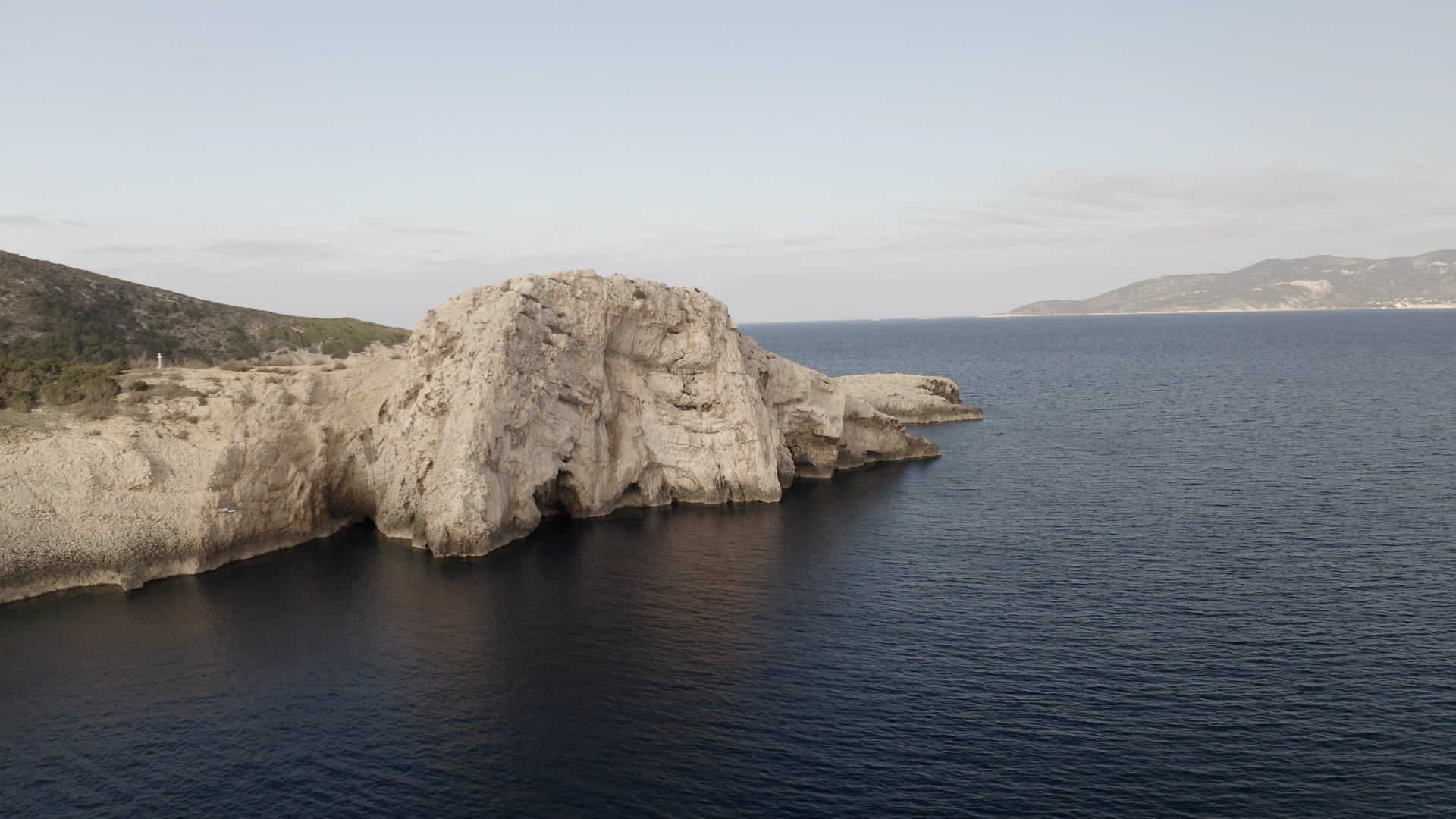Panned view of the small cliff near the sea, few houses and forest in the background