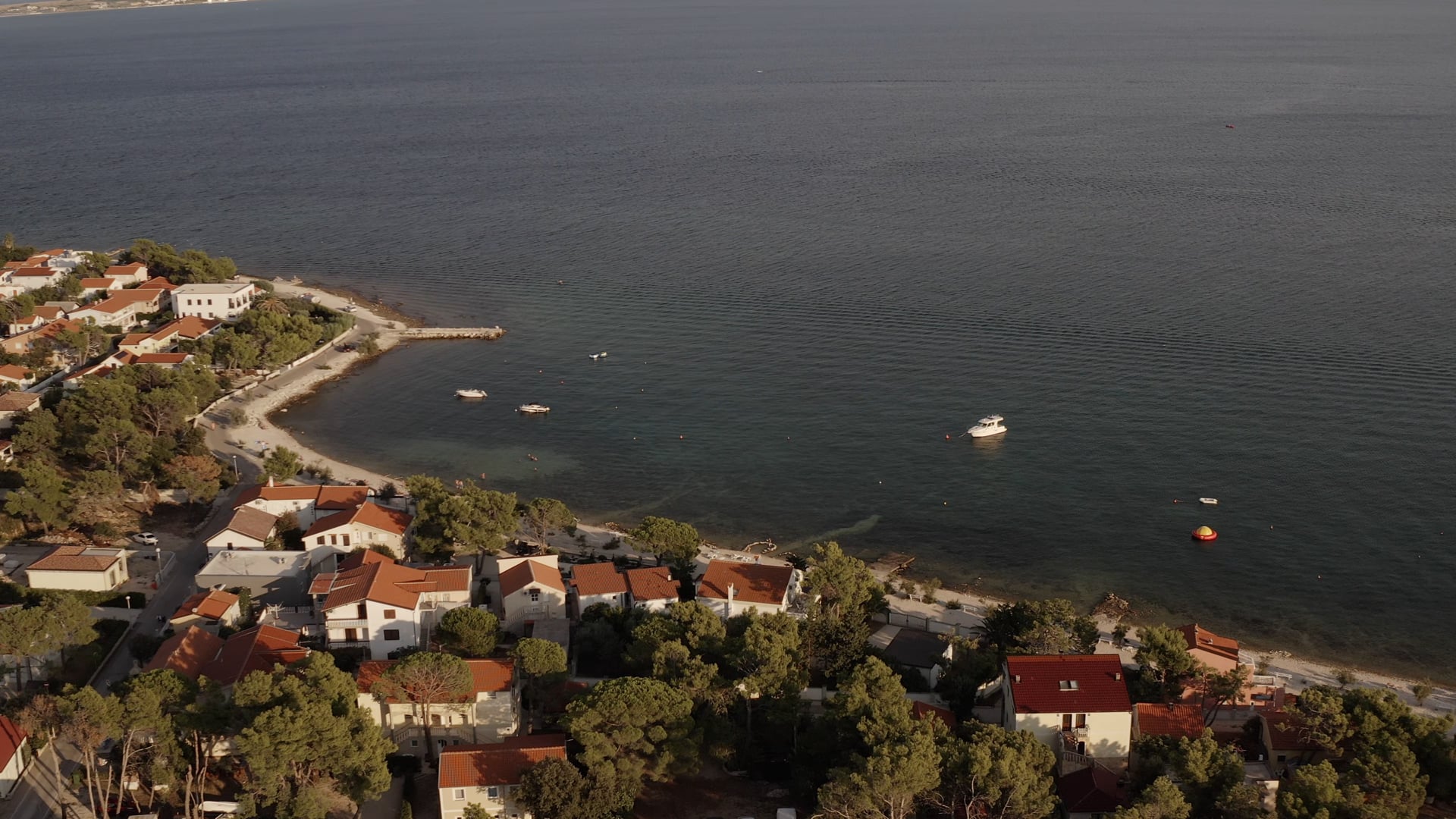Houses at the seaside, one small yacht and few small boats near the pier