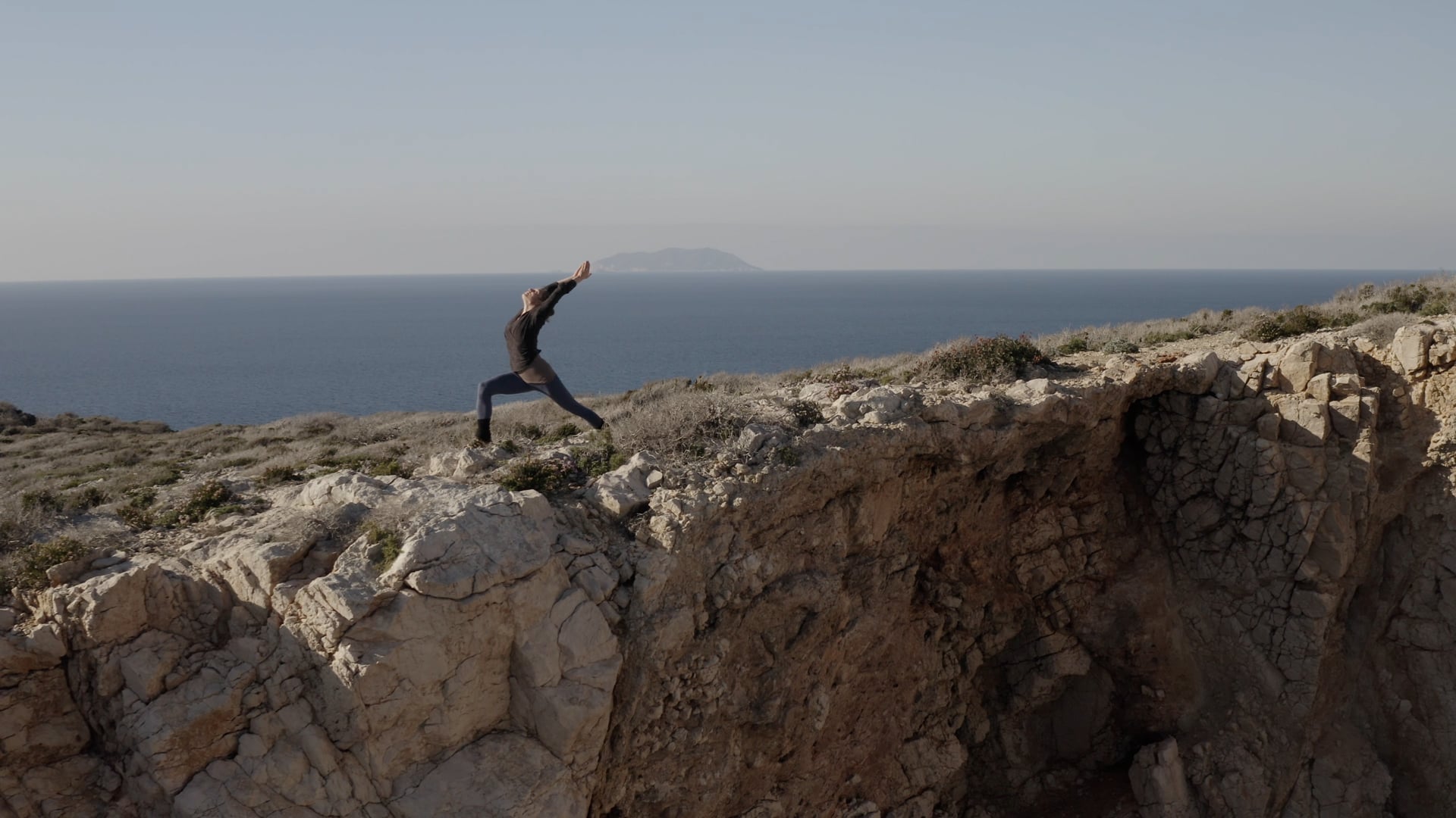Women practicing yoga at the top of the island, sea and other island visible in the distance