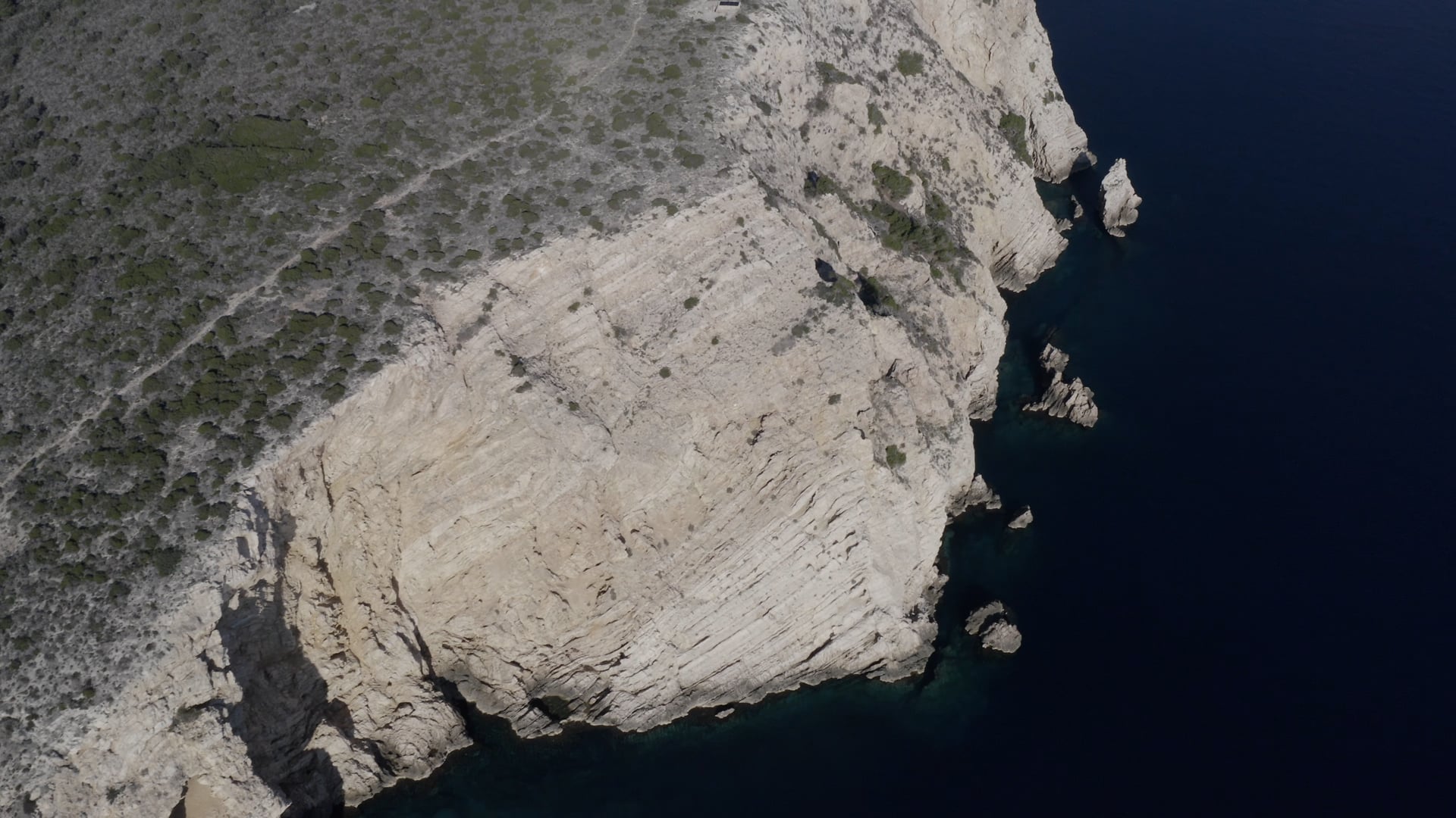Cliff near the deep blue sea, small bushes on the top of the cliff