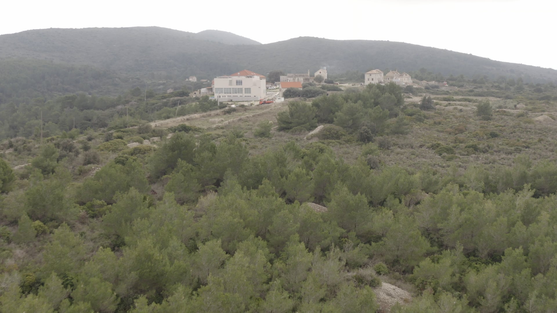 Few houses and orange truck in the middle of the forest