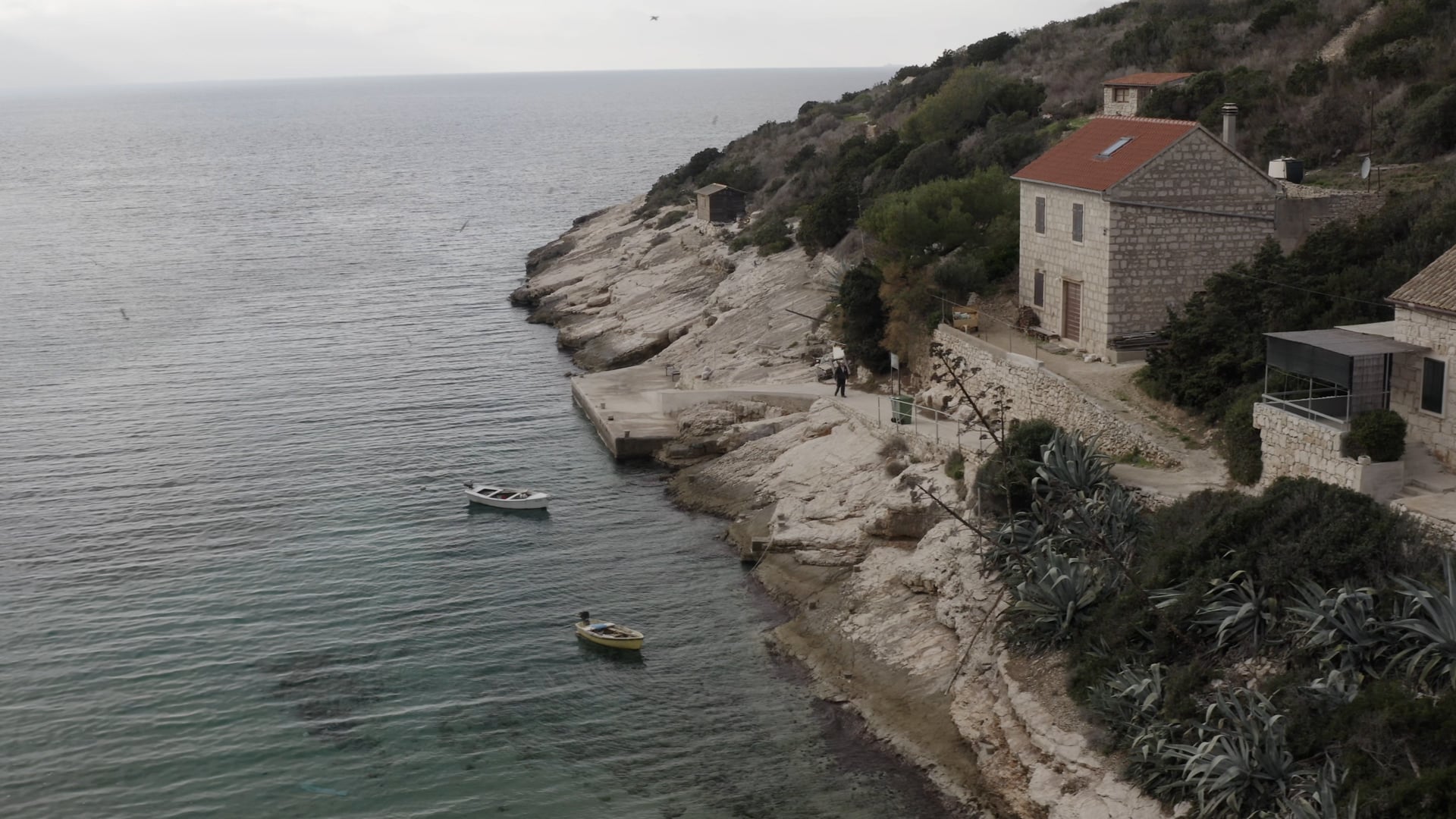 Two boats in the small bay, old man walking up the hill