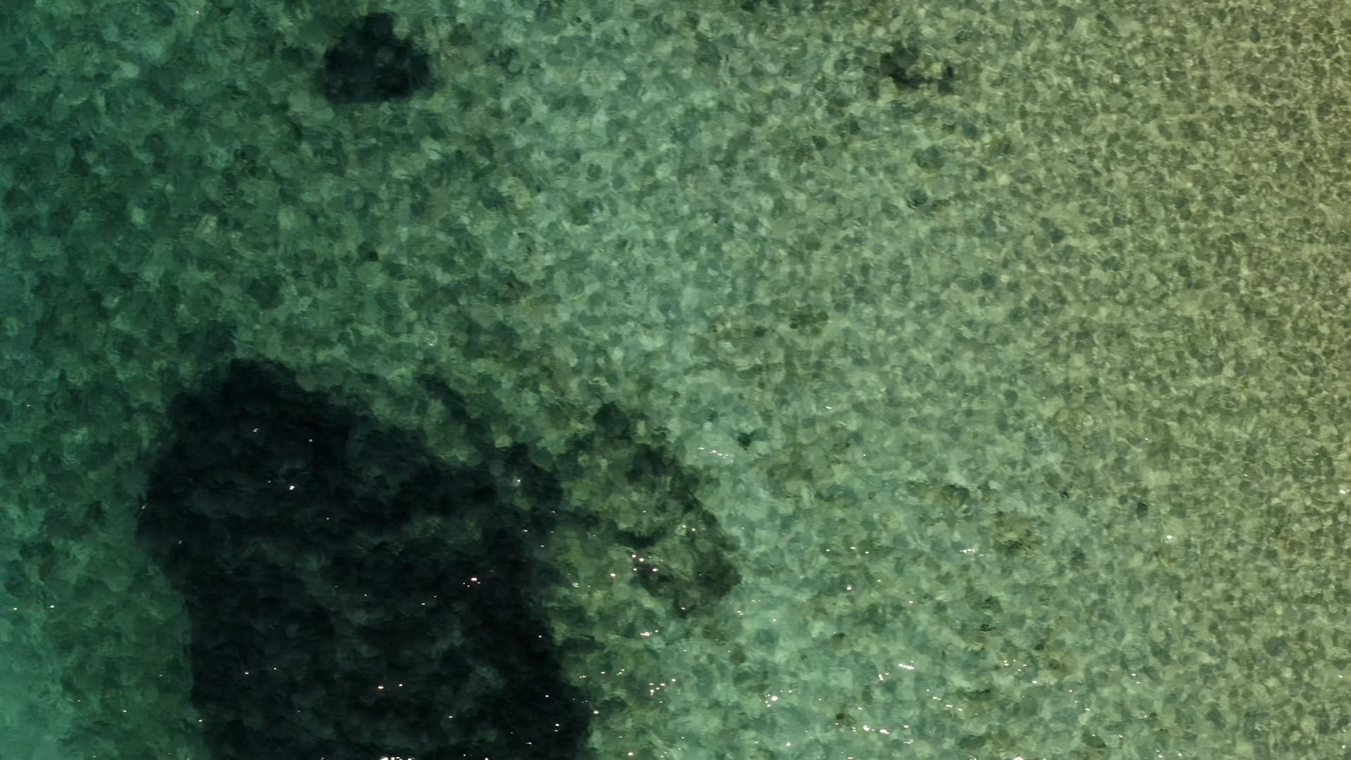 Crystal clear light blue sea, close up top view, apporaching the coast