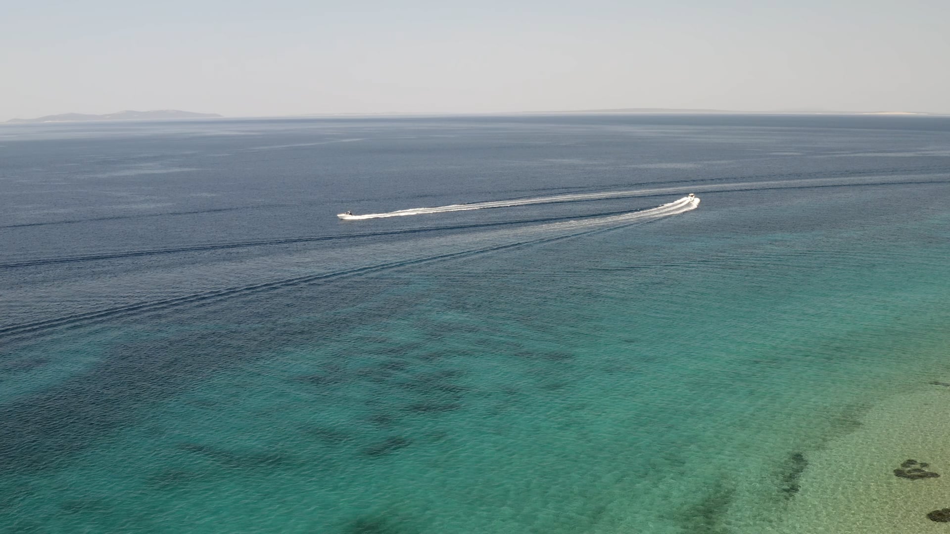 Two boats passing by each other, crystal clear blue sea