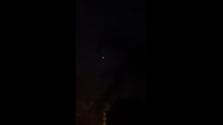 An orange light in the night sky above a palm tree in Palm Springs.