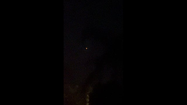 An orange light in the night sky above a palm tree in Palm Springs.