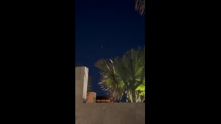 A small light above palm fronds and resort walls in Cabo San Lucas.
